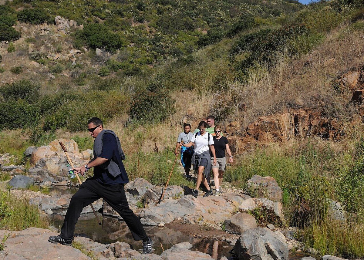 chaparral-covered hills and rock outcroppings along a trail with the San Diego skyline in the distance